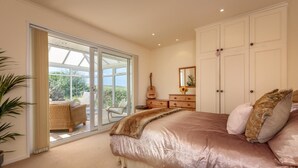 A bedroom with a large bed, a guitar, a dresser, and a sliding glass door leading to a balcony. - 2 Bed in Bwlchtocyn (oc-brynxx) (Bwlchtocyn)