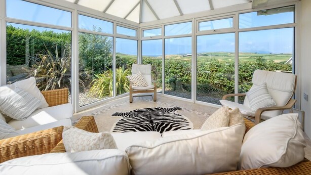 A sunroom with large windows, a zebra-patterned rug, and a view of a vineyard. - 2 Bed in Bwlchtocyn (oc-brynxx) (Bwlchtocyn)