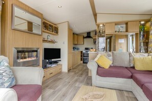 Interior moderno de autocaravana con sala de estar, kitchenette y chimenea.