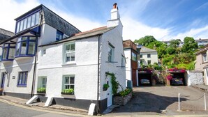 A white building with blue trim and a garage with flower boxes. - 2 Bed in West Looe (oc-l30054) (Looe)