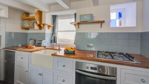 A modern kitchen with a wooden countertop, stainless steel appliances, and a window providing natural light. - 2 Bed in West Looe (oc-l30054) (Looe)