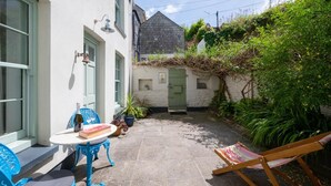 Une cour avec une table, des chaises et un hamac.