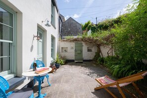 Une cour avec une table, des chaises et un hamac.