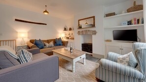Un salon confortable avec un ensemble de canapés, une table basse, un téléviseur et une cheminée.