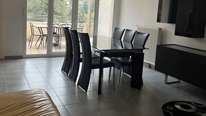 Una moderna camera d'hotel con un letto grande, un'area pranzo con sedie, un tavolo e una lampada a sospensione.