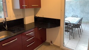 Una cucina compatta con un piano di lavoro nero, mobili rossi e una finestra.