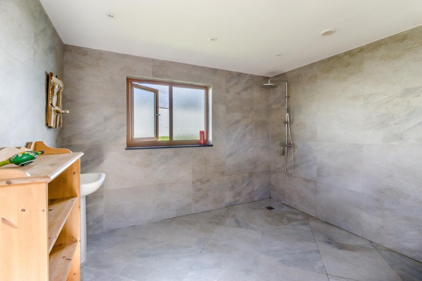 Une salle de bain moderne avec une douche, une fenêtre et un meuble-lavabo en bois.