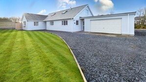 Une maison à deux étages, à l’extérieur blanc, avec un garage et une pelouse bien entretenue.