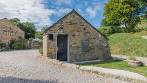 Un petit bâtiment en pierre avec une porte noire et une enseigne sur laquelle on peut lire : « Auberge de Troffany ».