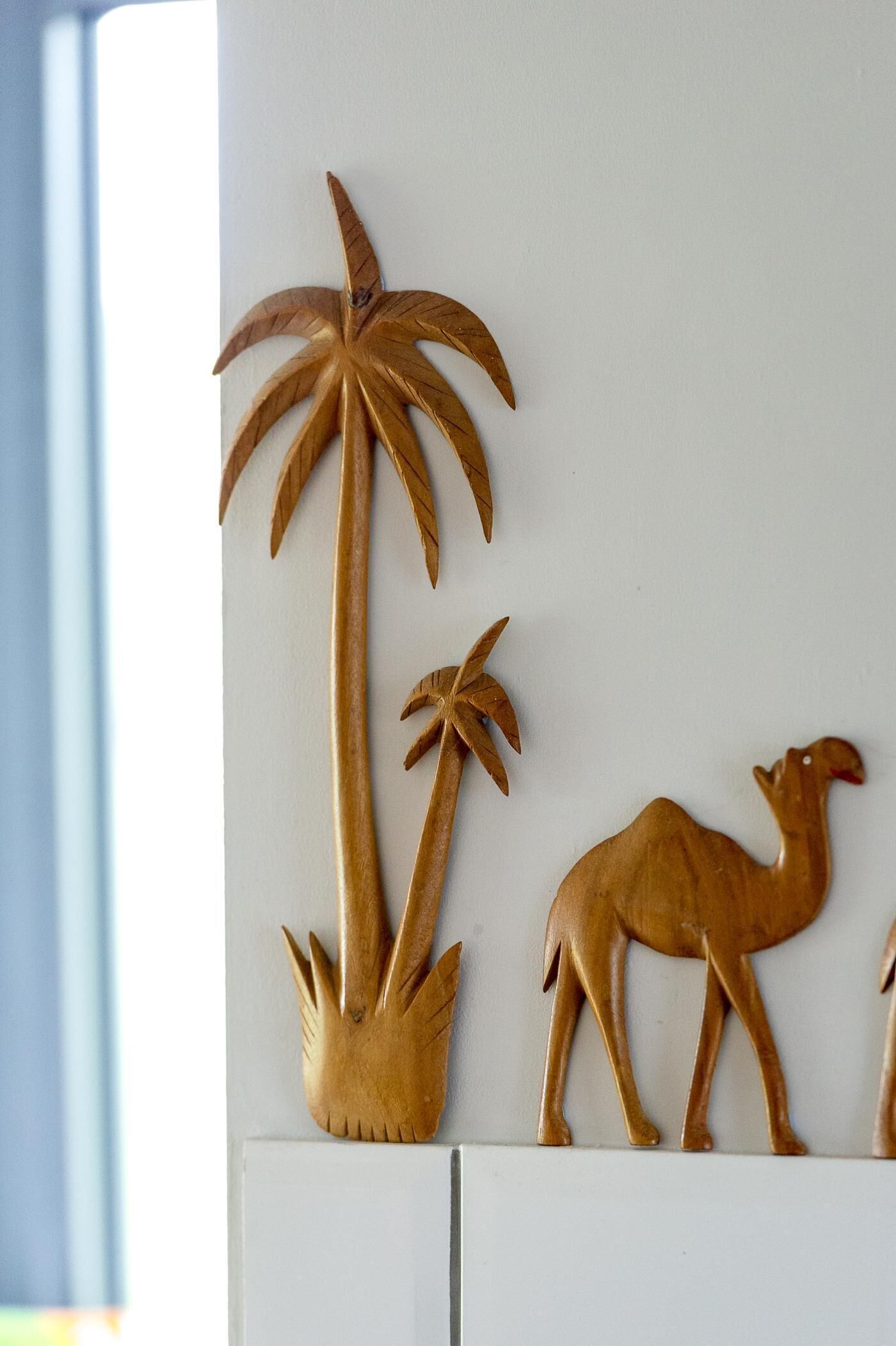 Een muur met houten houtsnijwerken van een palmboom en een kameel.