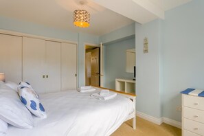 A bedroom with a bed, a bedside table, a dresser, a mirror, and a hanging light fixture. - 2 Bed in Aldeburgh (oc-7cc) (Aldeburgh)