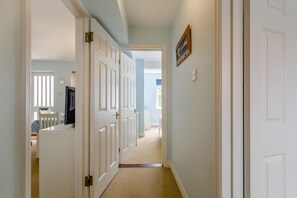 A hallway with white doors, a carpeted floor, and a view into another room with a bed and a window. - 2 Bed in Aldeburgh (oc-7cc) (Aldeburgh)
