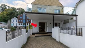 Ein überdachter Außenbereich mit einem gepflasterten Weg, der zu einem Hauseingang führt.