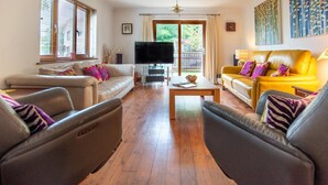 Een woonkamer met een bank, fauteuils, een salontafel en een televisie.