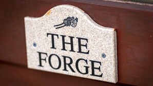 Een bord met de tekst 'THE FORGE' op een structuurrijk oppervlak.