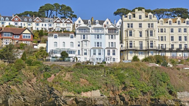 Ein Küstenhotel im viktorianischen Stil, das auf einer Klippe mit Blick auf das Meer thront.