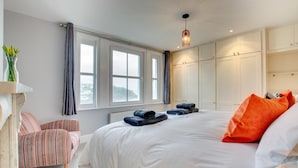 Ein Schlafzimmer mit einem großen Bett, einem Sessel, einem Kleiderschrank und einem Fenster.
