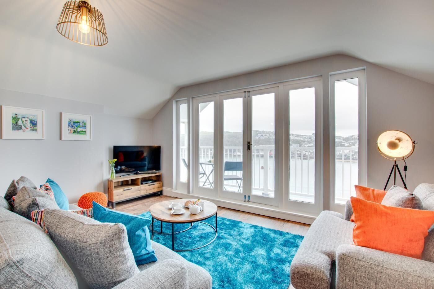 A spacious living room with a large window, a television, and a round coffee table.