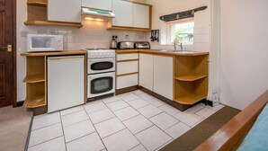 A compact kitchen with white cabinets, a microwave, an oven, and a toaster.