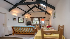 A cozy room with a bed, a dining table set for two, and a TV in the corner.