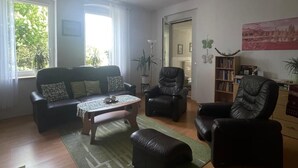 A living room with a sofa, two armchairs, a coffee table, and a bookshelf. - Vacation in the countryside with a pet (Rathenow)