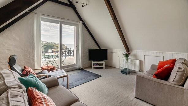 A modern living room with a sloped ceiling, a large window, and a flat-screen TV. - 2 Bed in Fowey (oc-p00839) (Fowey)