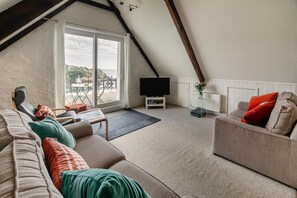 Een moderne woonkamer met een schuine plafond, een groot raam en een flatscreen televisie.
