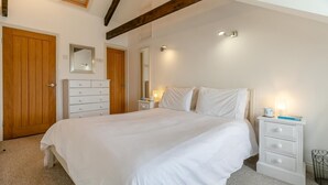 A bedroom with a large bed, a dresser, a nightstand, and a wooden door. - 2 Bed in Fowey (oc-p00839) (Fowey)