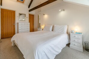 A bedroom with a large bed, a dresser, a nightstand, and a wooden door. - 2 Bed in Fowey (oc-p00839) (Fowey)