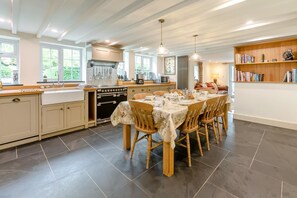 A modern kitchen with a dining area, large windows, and a bookshelf.