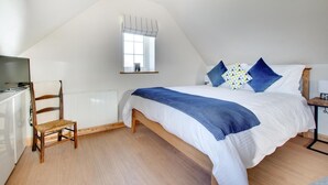 A bedroom with a bed, a chair, a desk, and a window.