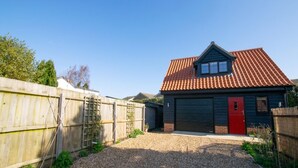 A single-story house with a red door, a garage, and a gravel driveway.