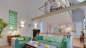 A modern living room with a green sofa set, a coffee table, and a staircase leading to an upper level. - 2 Bed in Fowey (oc-p00703) (Fowey)