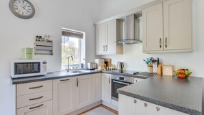 A modern kitchen with white cabinets, a microwave, a toaster, and a kettle. - 2 Bed in Llaniestyn (oc-gweger) (Llaniestyn)