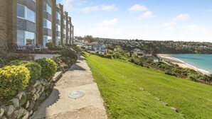 A coastal hotel with a paved walkway, a grassy lawn, and a view of the beach and ocean. - 2 Bed in St Ives (oc-gmn19) (Carbis Bay)