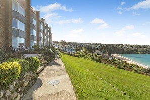 A coastal hotel with a paved walkway, a grassy lawn, and a view of the beach and ocean. - 2 Bed in St Ives (oc-gmn19) (Carbis Bay)