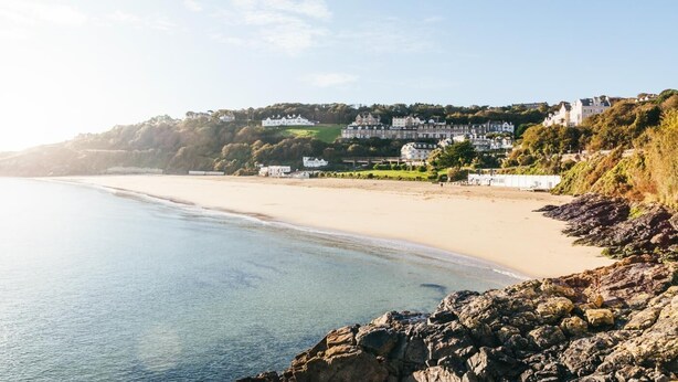 A coastal beach with a rocky shoreline, a sandy beach, and a row of white buildings on a hillside. - 2 Bed in St Ives (oc-gmn19) (Carbis Bay)