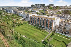 En bostadsbyggnad med en central innergård, omgiven av grönska och andra hus.