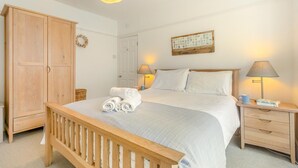 Une chambre à coucher comprenant un lit, une armoire en bois, une table de chevet avec une lampe et un collage de photos accroché au mur.