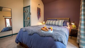 Ein Schlafzimmer mit einem großen Bett, einem Nachttisch mit Lampe und einem Spiegel an der Wand.