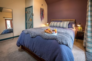 A bedroom with a large bed, a bedside table with a lamp, and a mirror on the wall. - 2 Bed in Llannor (oc-cysgul) (Efailnewydd)