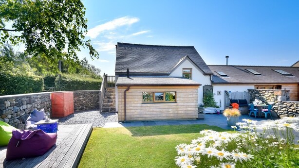 Ein Haus mit gepflegtem Rasen, einer Sitzterrasse und einem Blumengarten.