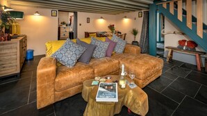 Ein gemütliches Wohnzimmer mit einem braunen Ledersofa, einem Holztisch und einer Treppe mit Holzbalken.