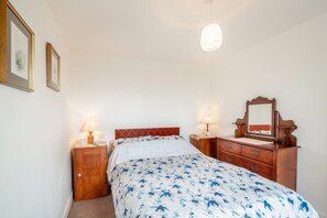 A bedroom with a bed, two bedside tables, a dresser, a mirror, and a hanging light fixture. - 3 Bed in Aberdaron (oc-wag407) (Aberdaron)