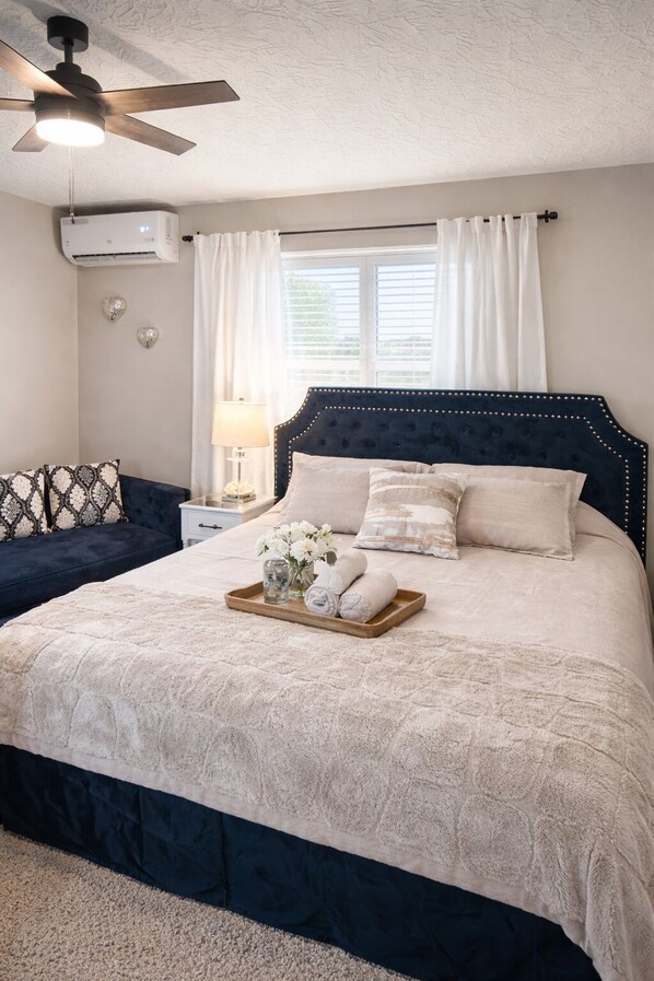 A bedroom with a bed, bedside table, lamp, and a ceiling fan.