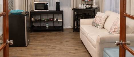 A living room with a sofa, a coffee table, a TV stand, and a ceiling fan.
