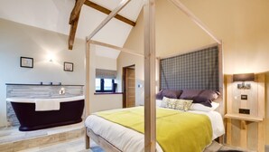 Un dormitorio con cama con dosel, una bañera y un ventanal pequeño.