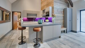 Una cocina moderna con una isla central, taburetes de bar y vista al área de estar contigua.