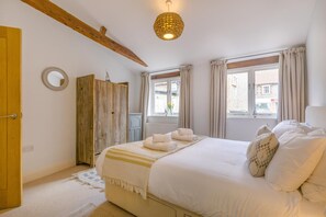 A bedroom with a bed, a wooden wardrobe, a window with curtains, and a hanging light fixture. - 4 Bed in Blakeney (oc-1948) (Blakeney)