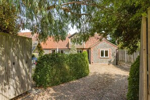 A residential property with a gravel driveway, a wooden fence, and a stone wall. - 4 Bed in Blakeney (oc-1948) (Blakeney)